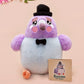 An adorable purple and blue pigeon bird plushie toy with cute embroidered eyes and facial expression, wearing a black top hat and bow tie, with a hang tag describing the pigeon as Susan.