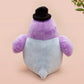 An adorable purple and blue pigeon bird plushie toy with cute embroidered eyes and facial expression, wearing a black top hat and bow tie, with a hang tag describing the pigeon as Susan.