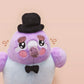An adorable purple and blue pigeon bird plushie toy with cute embroidered eyes and facial expression, wearing a black top hat and bow tie, with a hang tag describing the pigeon as Susan.