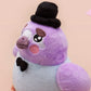 An adorable purple and blue pigeon bird plushie toy with cute embroidered eyes and facial expression, wearing a black top hat and bow tie, with a hang tag describing the pigeon as Susan.