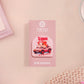 Clear acrylic pin badge with a pink heart-shaped rubber pin back clasp. The design of the pin badge is a cute chibi guinea pig hamster driving a pink car and the quote the horrors do be persisting.