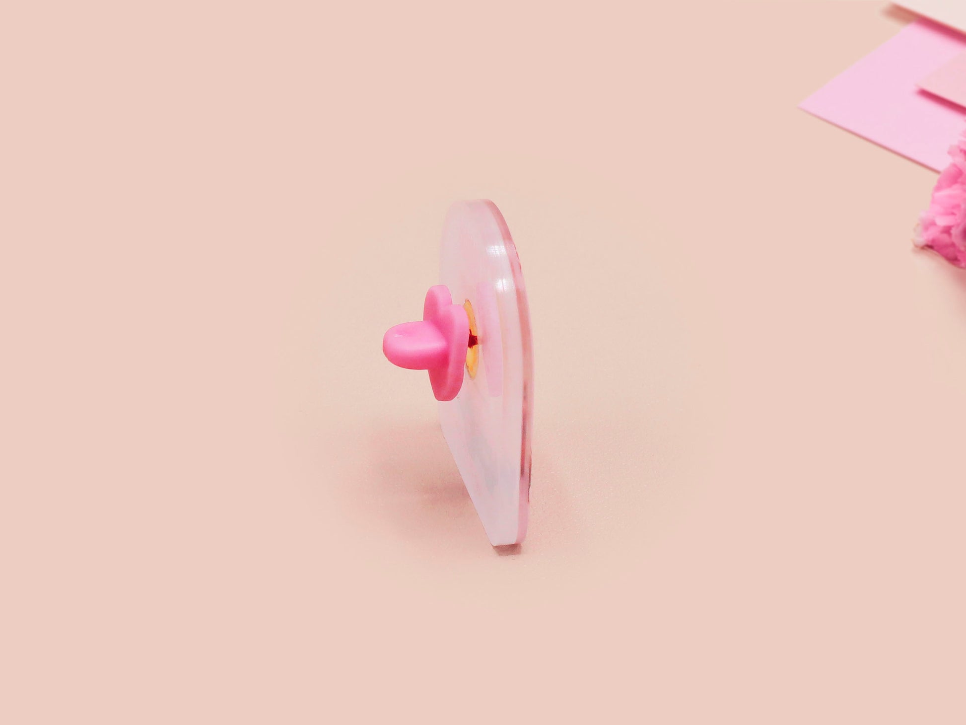 Clear acrylic pin badge with a pink heart-shaped rubber pin back clasp. The design of the pin badge is a cute chibi guinea pig hamster driving a pink car and the quote the horrors do be persisting.
