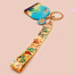 Acrylic epoxy dinosaur keychain with a large acrylic charm of a long necked dinosaur looking up at an incoming asteroid with the quote uh oh, a smaller charm of a cute trex with arm grabbers and a matching hatching baby dinosaur lanyard.