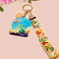 Acrylic epoxy dinosaur keychain with a large acrylic charm of a long necked dinosaur looking up at an incoming asteroid with the quote uh oh, a smaller charm of a cute trex with arm grabbers and a matching hatching baby dinosaur lanyard.