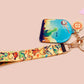 Acrylic epoxy dinosaur keychain with a large acrylic charm of a long necked dinosaur looking up at an incoming asteroid with the quote uh oh, a smaller charm of a cute trex with arm grabbers and a matching hatching baby dinosaur lanyard.