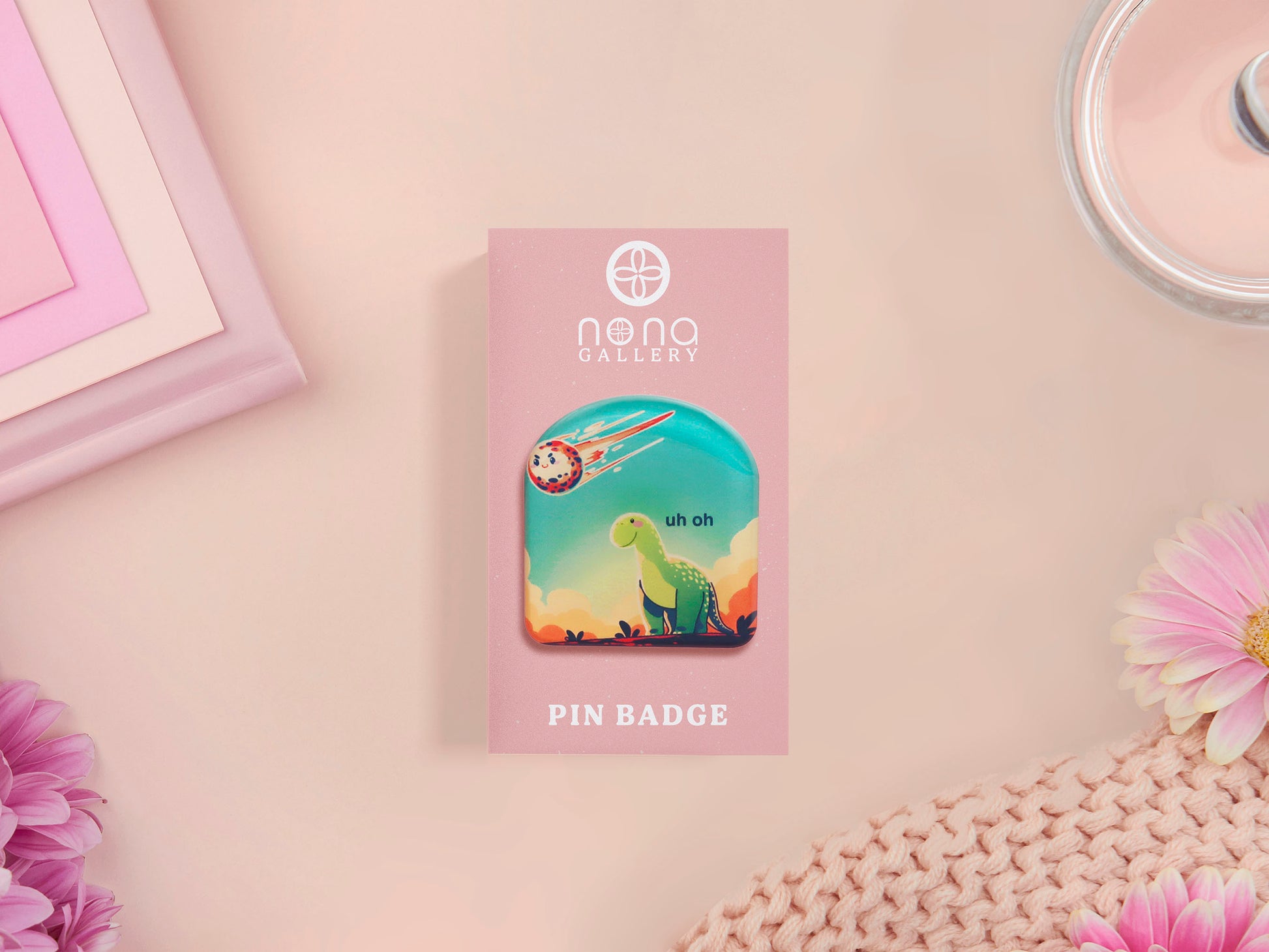 A clear acrylic pin badge with a pink heart-shaped pin back clasp. The design of the pin badge is of a cute long neck dinosur looking at an incoming asteroid with the quote uh oh.