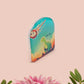A clear acrylic pin badge with a pink heart-shaped pin back clasp. The design of the pin badge is of a cute long neck dinosur looking at an incoming asteroid with the quote uh oh.