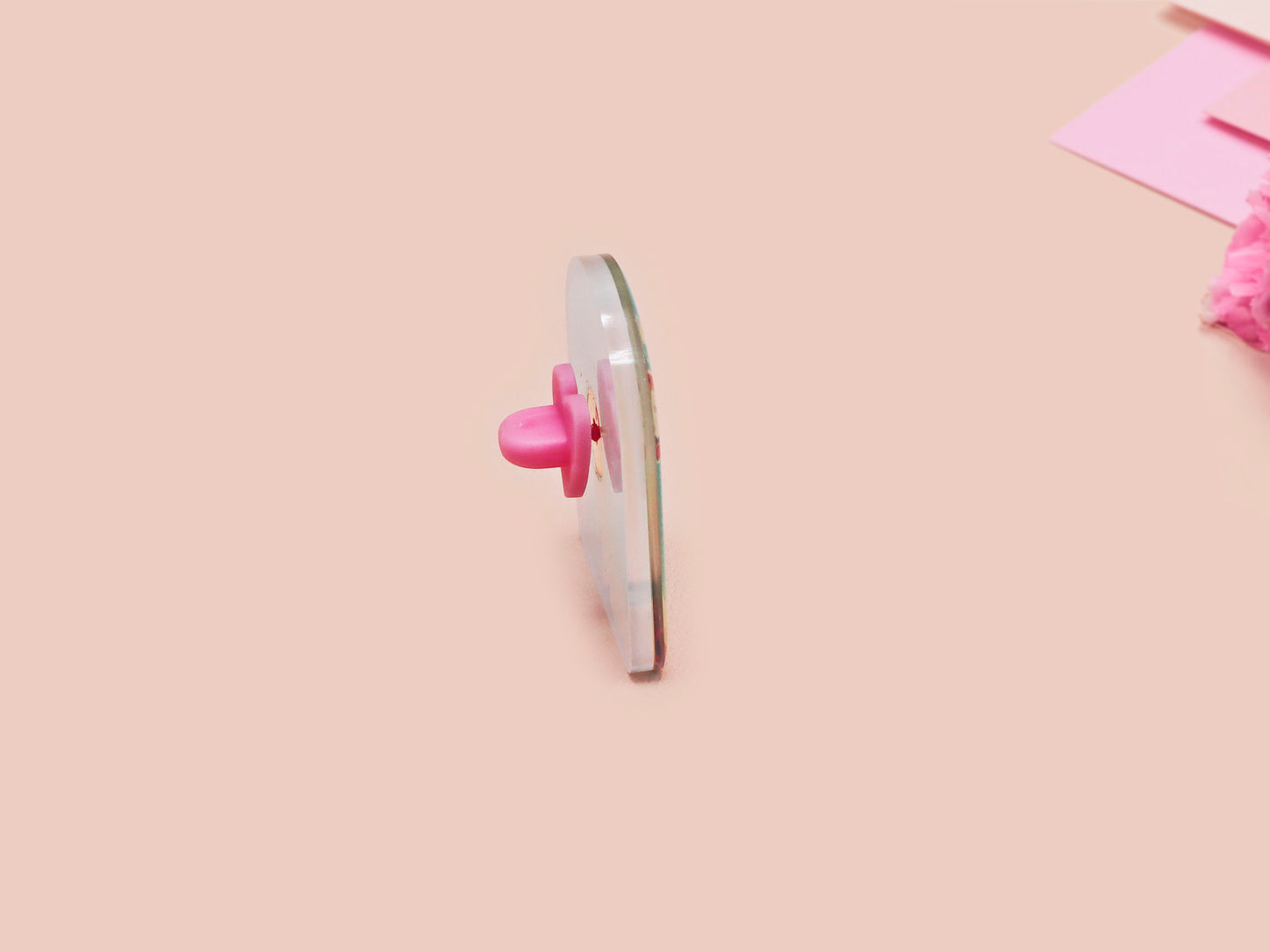 A clear acrylic pin badge with a pink heart-shaped pin back clasp. The design of the pin badge is of a cute long neck dinosur looking at an incoming asteroid with the quote uh oh.