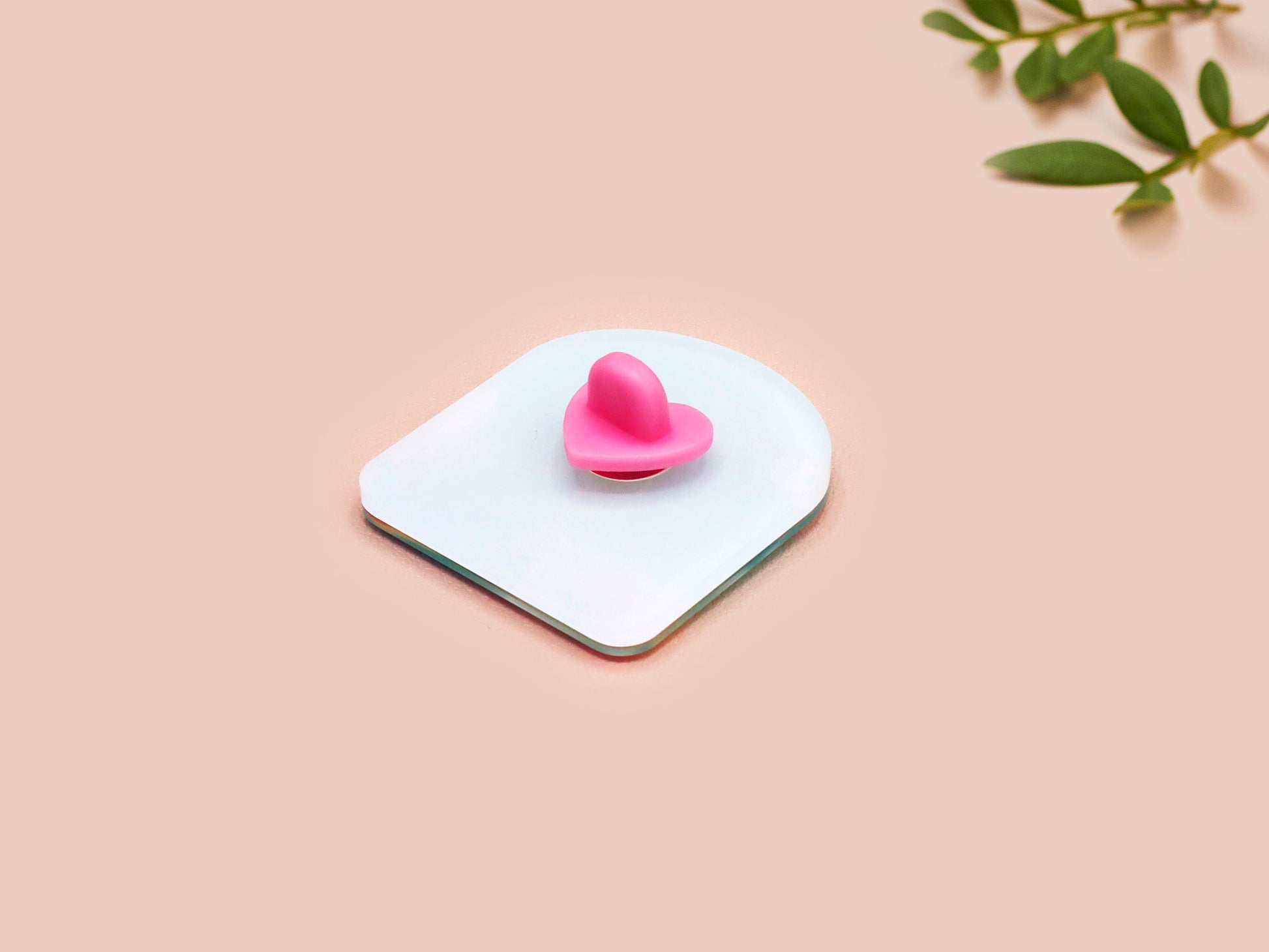 A clear acrylic pin badge with a pink heart-shaped pin back clasp. The design of the pin badge is of a cute long neck dinosur looking at an incoming asteroid with the quote uh oh.