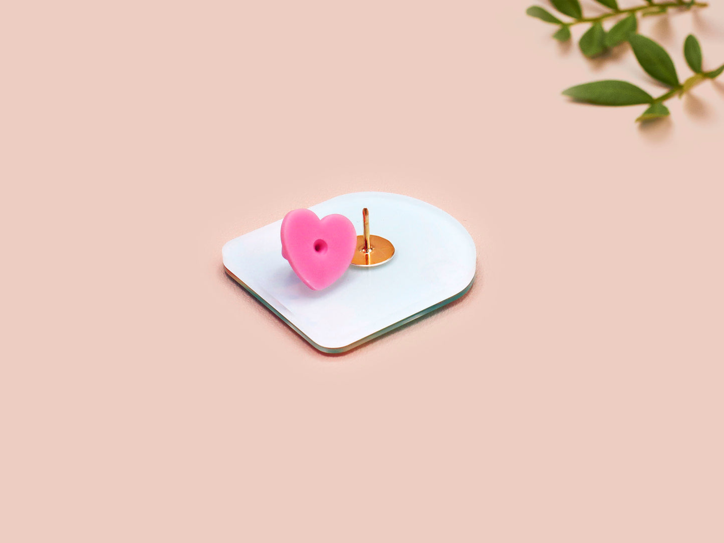 A clear acrylic pin badge with a pink heart-shaped pin back clasp. The design of the pin badge is of a cute long neck dinosur looking at an incoming asteroid with the quote uh oh.