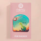 A clear acrylic pin badge with a pink heart-shaped pin back clasp. The design of the pin badge is of a cute long neck dinosur looking at an incoming asteroid with the quote uh oh.