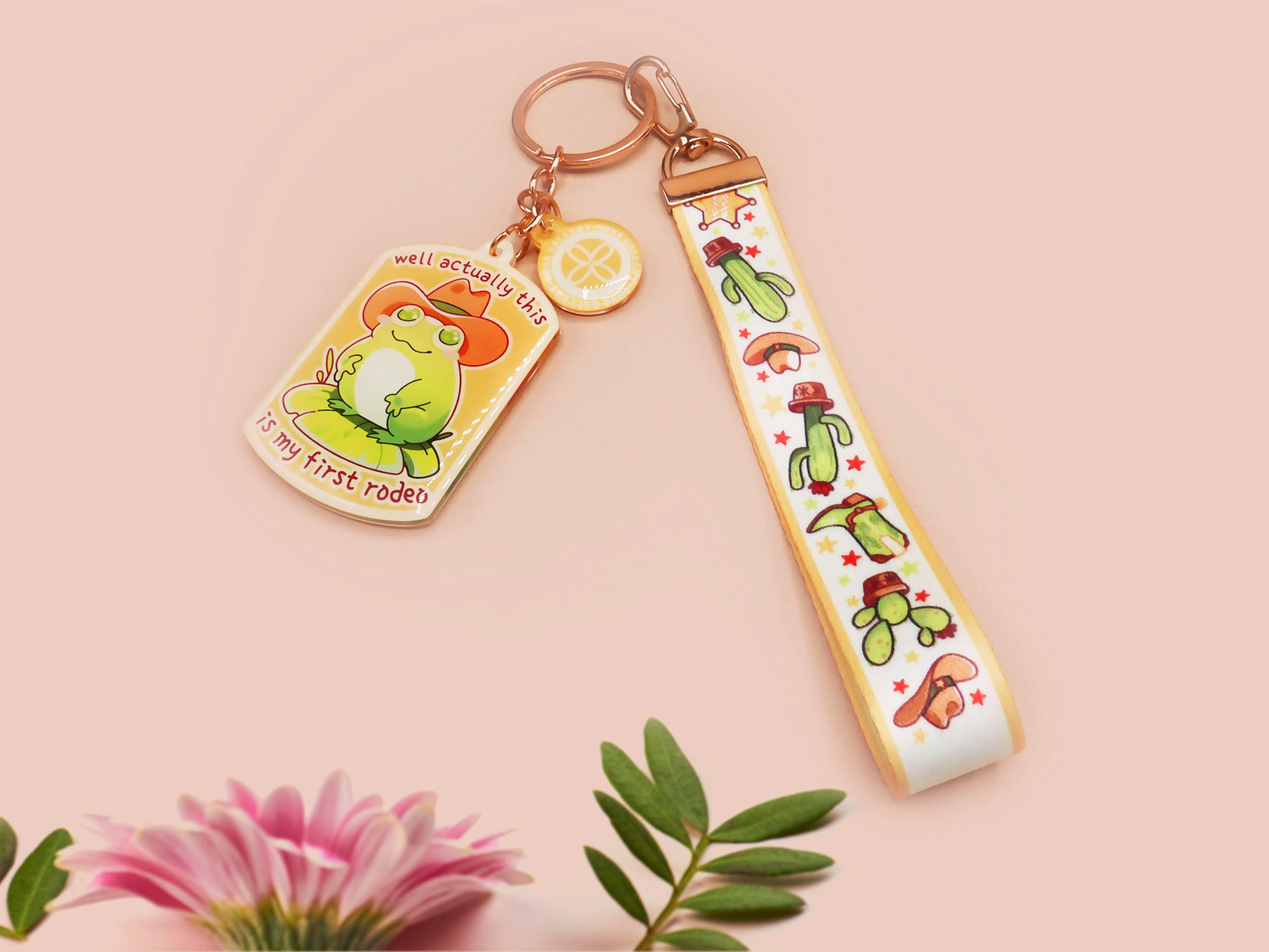 Acrylic keychain and lanyard of a cute cowboy frog with the quote well actually this is my first rodeo With a matching mini sherrif badge charm and lanyard of different country western items like cactus, stetsons and cowboy boots.