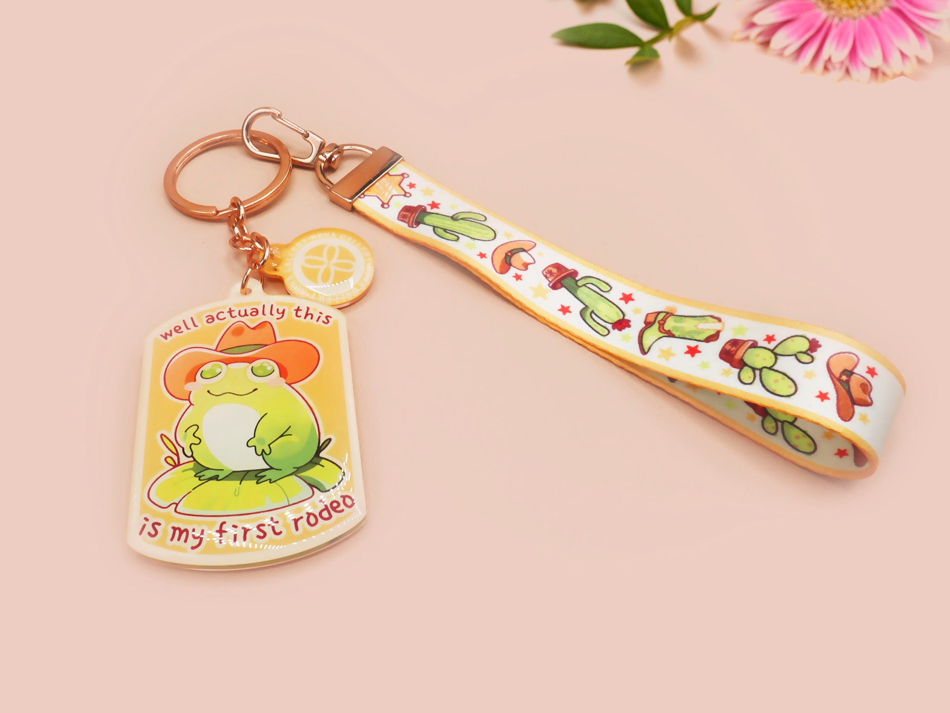 Acrylic keychain and lanyard of a cute cowboy frog with the quote well actually this is my first rodeo With a matching mini sherrif badge charm and lanyard of different country western items like cactus, stetsons and cowboy boots.