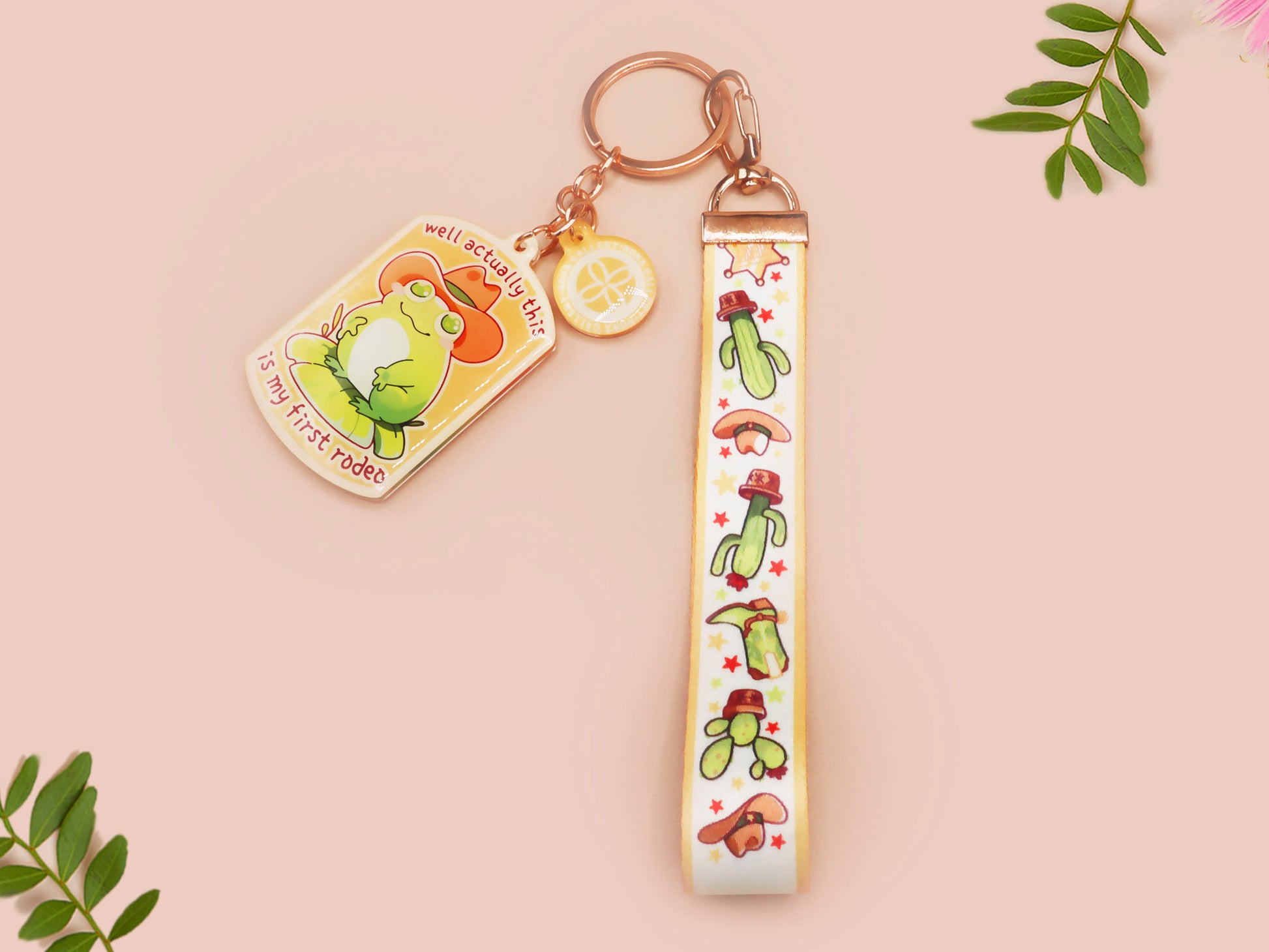 Acrylic keychain and lanyard of a cute cowboy frog with the quote well actually this is my first rodeo With a matching mini sherrif badge charm and lanyard of different country western items like cactus, stetsons and cowboy boots.