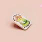 Clear acrylic pin badge with a pink heart-shaped rubber pin back clasp. The design of the pin badge is a cute chibi frog wearing a cowboy hat stetson and the quote well actually this is my first rodeo.
