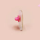 Clear acrylic pin badge with a pink heart-shaped rubber pin back clasp. The design of the pin badge is a cute chibi frog wearing a cowboy hat stetson and the quote well actually this is my first rodeo.