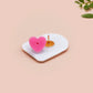 Clear acrylic pin badge with a pink heart-shaped rubber pin back clasp. The design of the pin badge is a cute chibi frog wearing a cowboy hat stetson and the quote well actually this is my first rodeo.