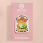 Clear acrylic pin badge with a pink heart-shaped rubber pin back clasp. The design of the pin badge is a cute chibi frog wearing a cowboy hat stetson and the quote well actually this is my first rodeo.