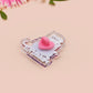 A clear acrylic pin badge with a heart-shaped pin rubber pin back clasp. The design of the pin badge is a cute cartoon screaming possum with the quote why me?!