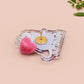 A clear acrylic pin badge with a heart-shaped pin rubber pin back clasp. The design of the pin badge is a cute cartoon screaming possum with the quote why me?!