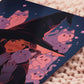 Square art print of a young witch wearing a large glowing witch's hat surrounded by nine cute chibi ghost cats.