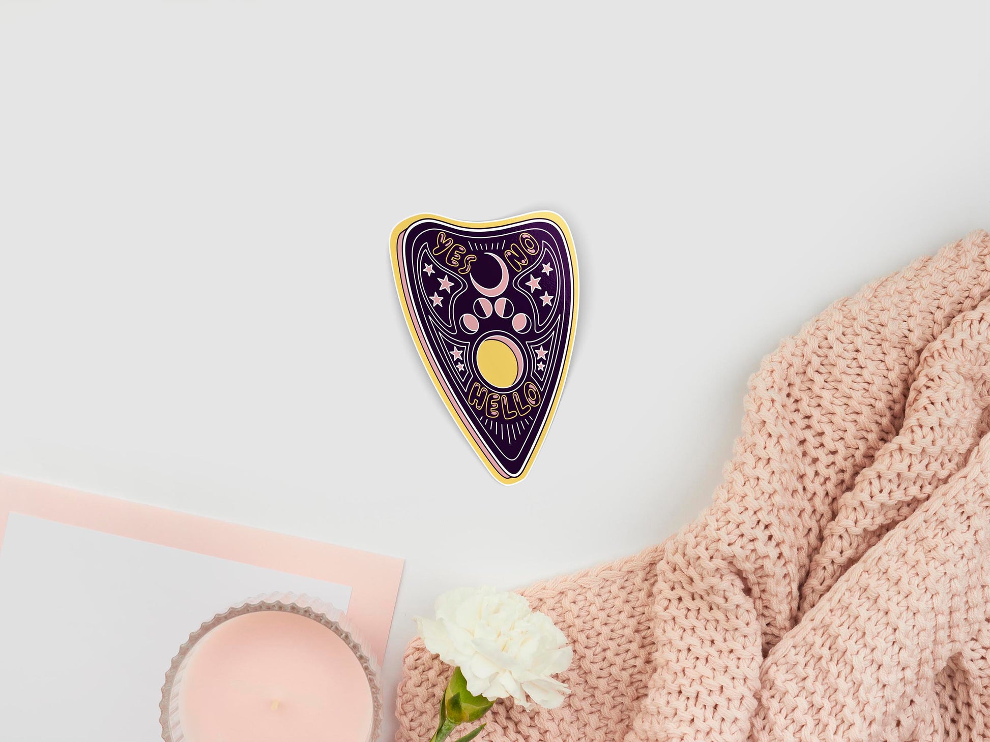 Large sticker of digital illustration cartoon dark purple and yellow Ouija Planchette with pink star and moon phases, and the words Yes, No, and Hello