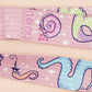 Cute full legth pink lanyard with a double sided funny worm on a string pattern and silver swivel hook clasp.