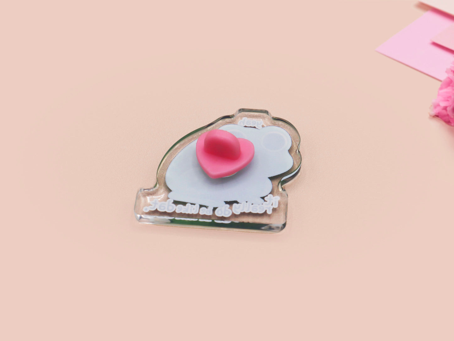 Clear acrylic pin badge with a pink heart-shaped rubber pin back clasp. The design of the pin badge is a cute cartoon stressed frog with the quote yeah it really do be like dat.