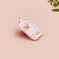 A clear acrylic pin badge with a pink heart-shaped pin back clasp. The design of the pin badge is of a cute chibi goose wearing a paper hat with the quote you silly goose.