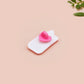 A clear acrylic pin badge with a pink heart-shaped pin back clasp. The design of the pin badge is of a cute chibi goose wearing a paper hat with the quote you silly goose.