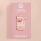 A clear acrylic pin badge with a pink heart-shaped pin back clasp. The design of the pin badge is of a cute chibi goose wearing a paper hat with the quote you silly goose.