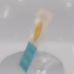 Video of front and back of Gold Enamel Talisman Pin with yellow design and the words Gamer's Talisman sits on a long white and blue backing card with gold accents. The backing card has details the symbolism of the different design elements of the Talisman pin.