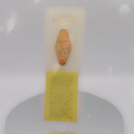 Video of the front and back of the Gold Enamel Talisman Pin with pink design and the words Fandom Talisman sits on a long white and yellow backing card with gold accents. The backing card has details the symbolism of the different design elements of the Talisman pin.