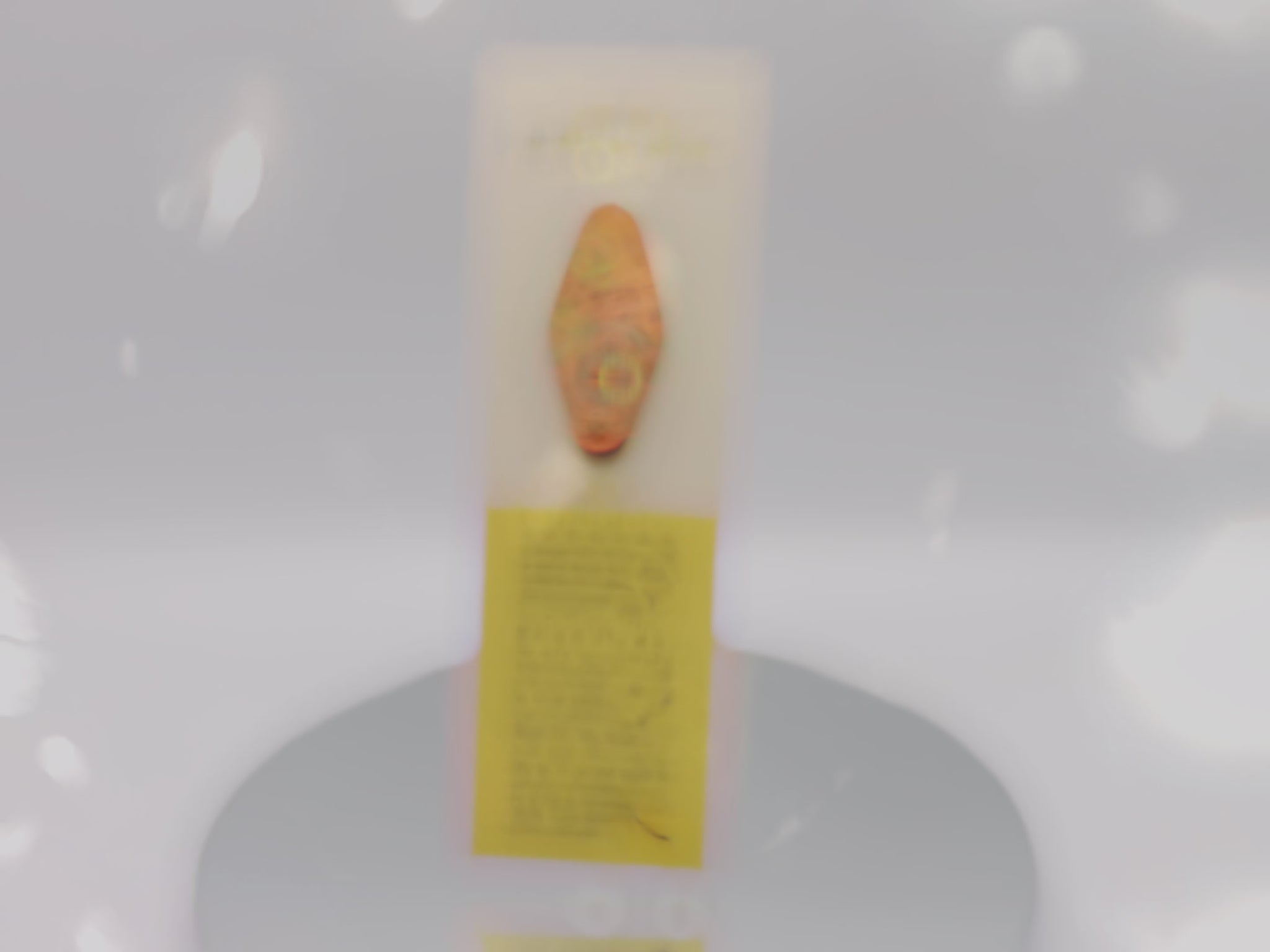 Video of the front and back of the Gold Enamel Talisman Pin with pink design and the words Fandom Talisman sits on a long white and yellow backing card with gold accents. The backing card has details the symbolism of the different design elements of the Talisman pin.
