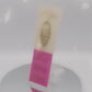 Video of the front and back of the Gold Enamel Talisman Pin with white design and the words Student's Talisman sits on a long white and pink backing card with gold accents. The backing card has details the symbolism of the different design elements of the Talisman pin.