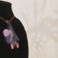 Video of mixed material handmade necklace of chibi cartoon bat hanging upside down holding a pearlescent Ouija planchette with a gold chain and necklace extender on black jewellery bust.