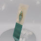 Video of the front and back of the Gold Enamel Talisman Pin with blue design and the words Musician's Talisman sits on a long white and blue backing card with gold accents. The backing card has details the symbolism of the different design elements of the Talisman pin.