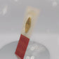 video of the front and back of the Gold Enamel Talisman Pin with brown design and the words Photographer's Talisman sits on a long white and red backing card with gold accents. The backing card has details the symbolism of the different design elements of the Talisman pin.