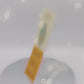 Video of front and back of gold Enamel Talisman Pin with blue design and the words Writer's Talisman sits on a long white and yellow backing card with gold accents. The backing card has details the symbolism of the different design elements of the Talisman pin.
