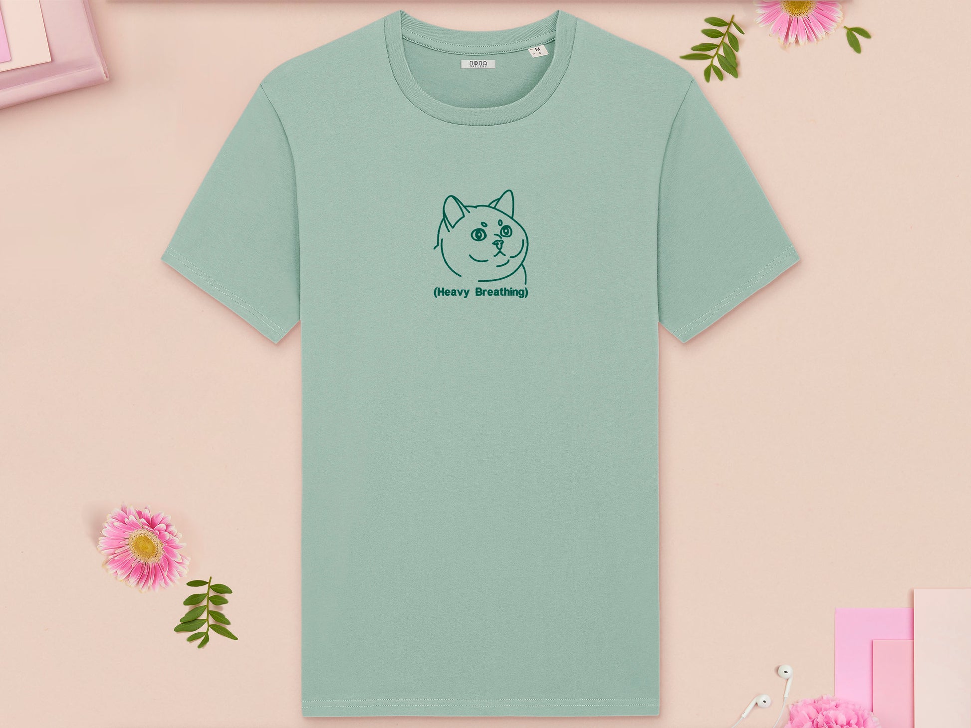 A green crew neck short sleeve t-shirt, with an embroidered green thread design of cute fat cat portrait with text underneath saying (Heavy Breathing)