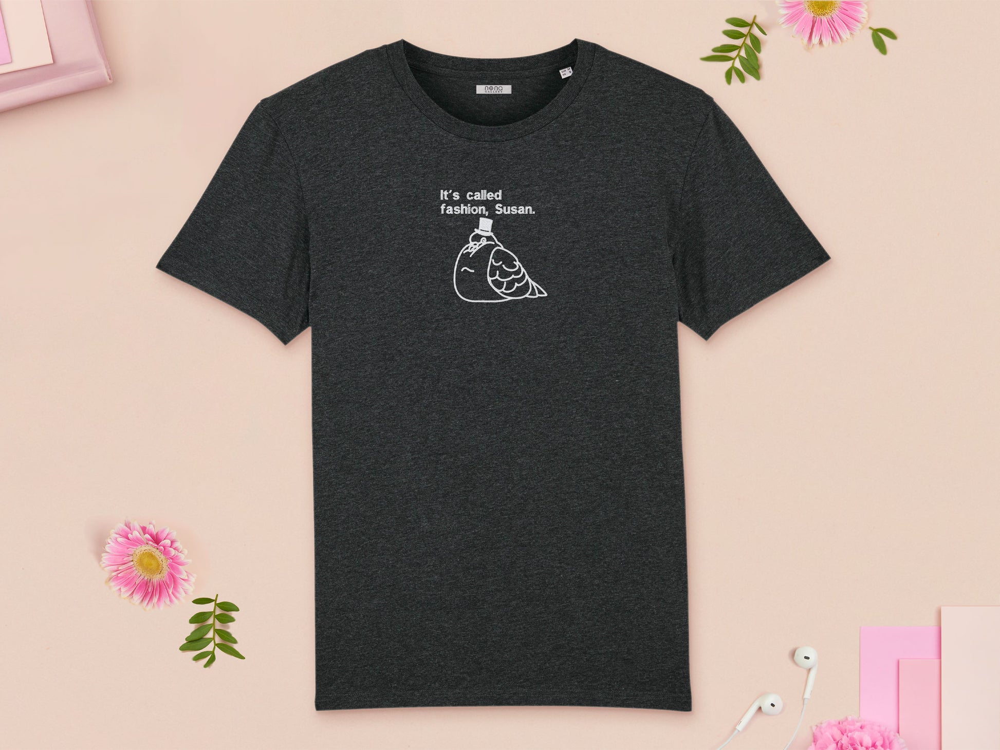 A grey crew neck short sleeve t-shirt, with an embroidered white thread design of cute fat pigeon wearing a top hat with text underneath reading It's Called Fashion, Susan.