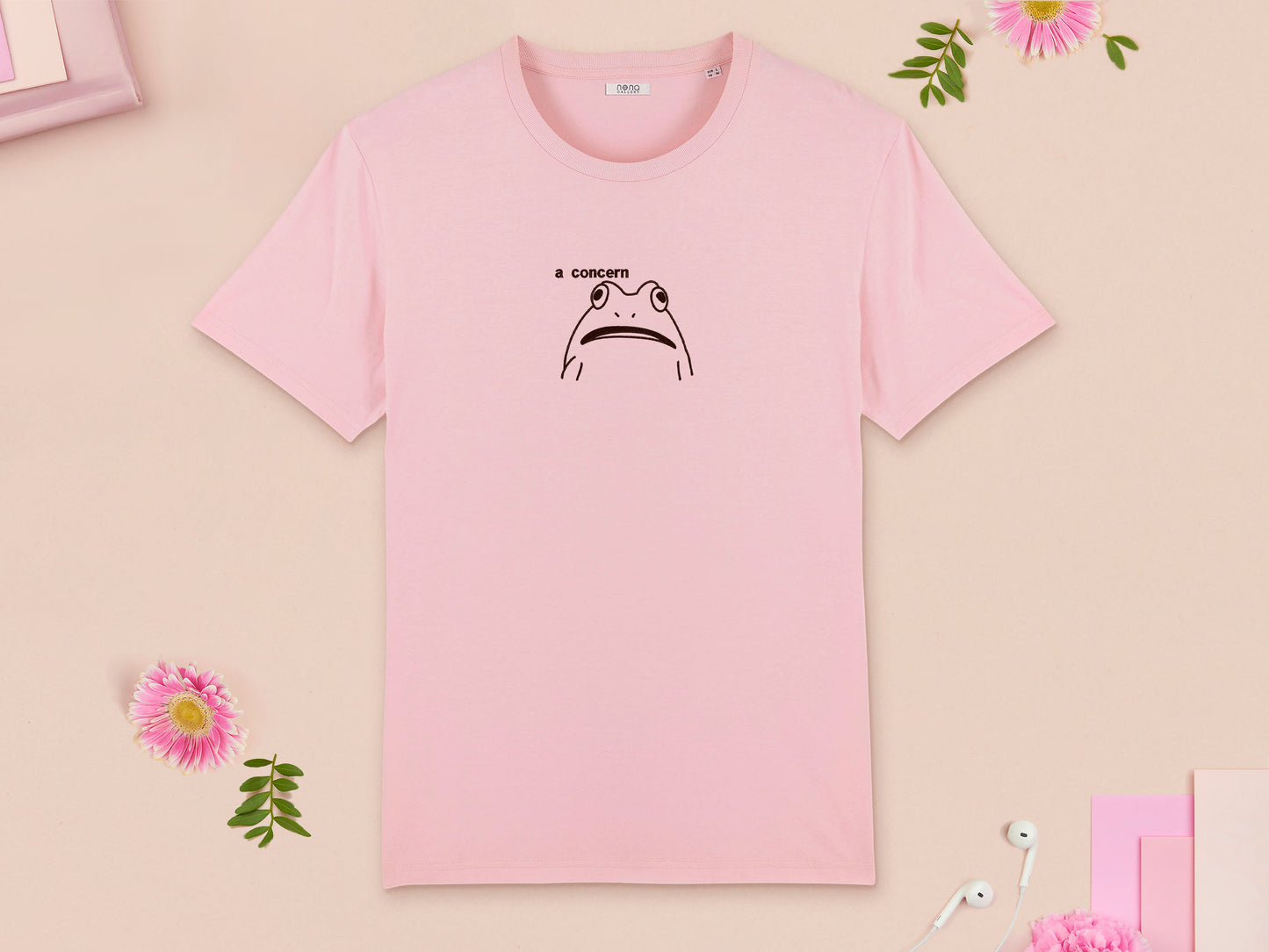 A pink crew neck short sleeve t-shirt, with an embroidered brown thread design of cute confused looking frog with the text a concern.