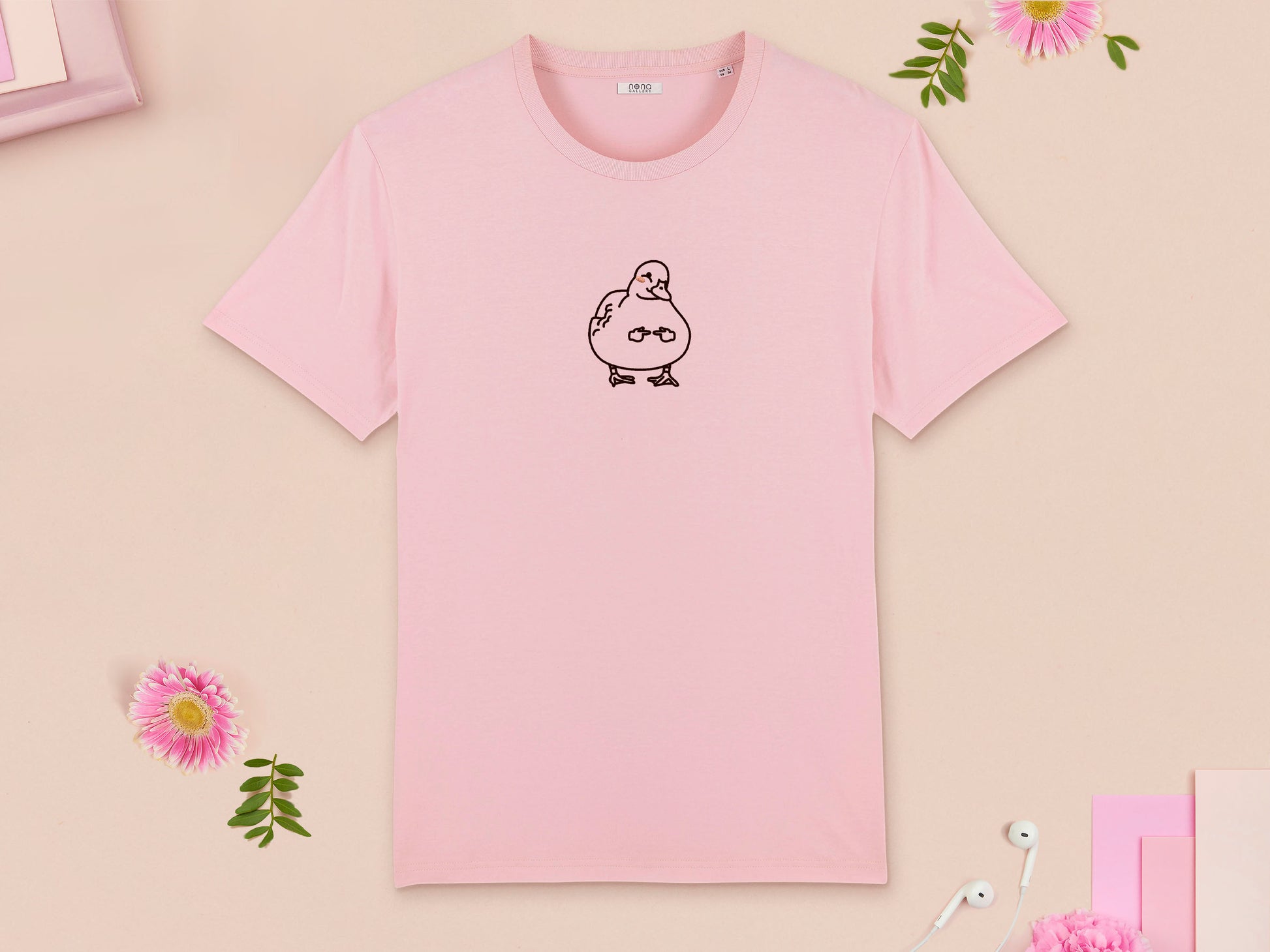 A pink crew neck short sleeve t-shirt, with an embroidered brown thread design of cute blushing duck with the for me finger hand emoji symbols
