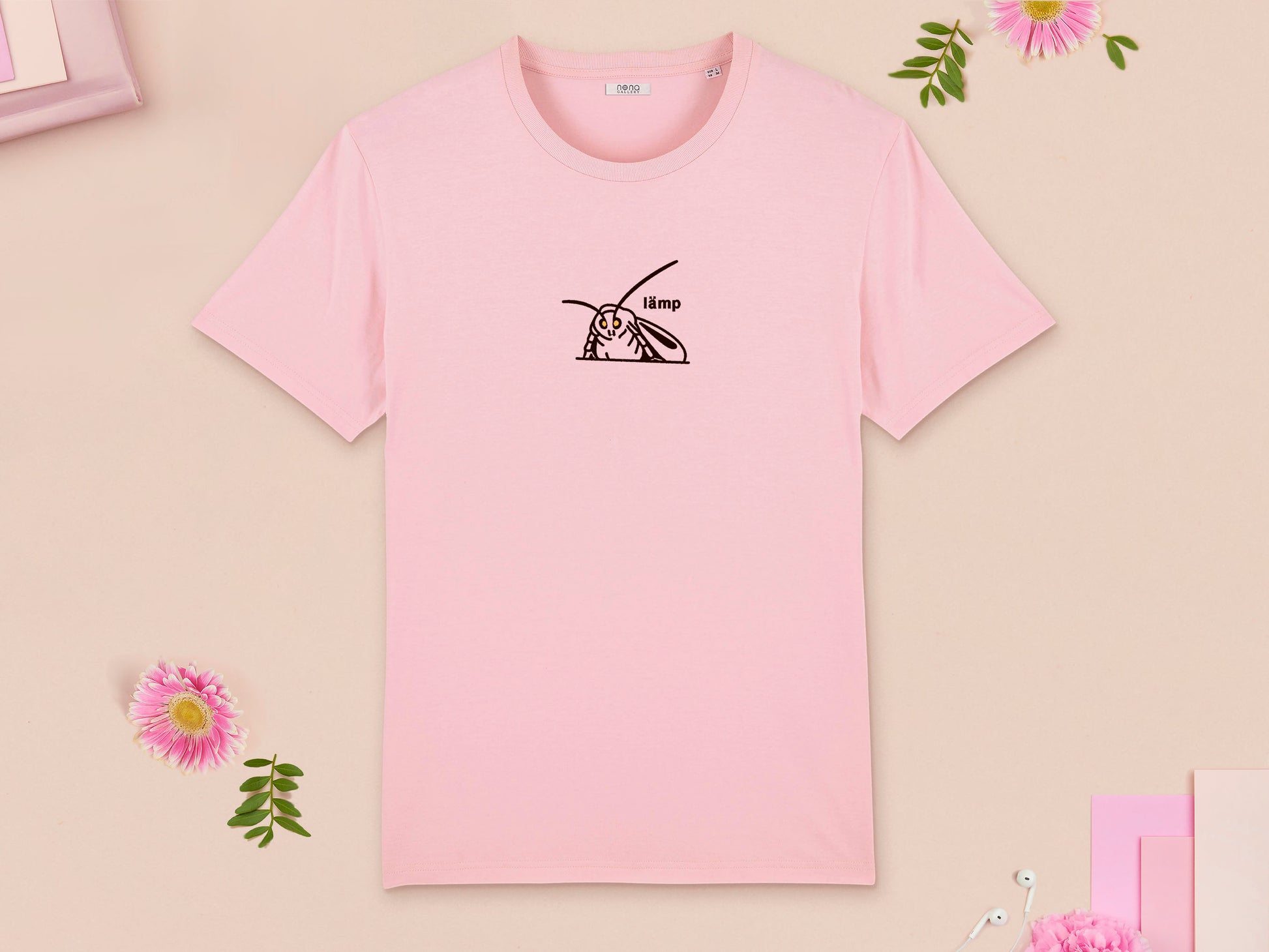 A pink crew neck short sleeve t-shirt, with an embroidered brown thread design of a moth with glowing yellow eyes and the word lämp