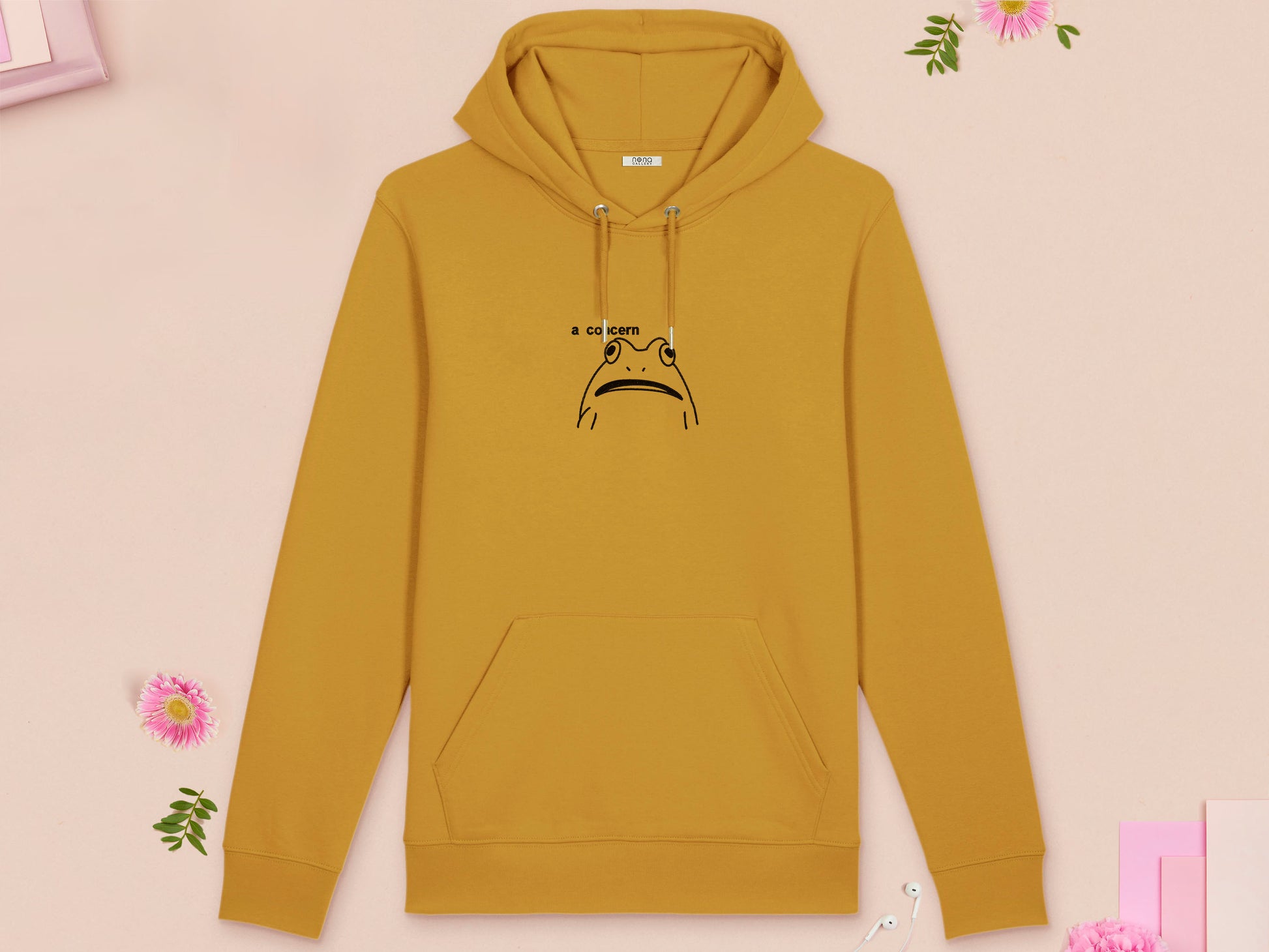 A yellow long sleeve fleece hoodie, with an embroidered black thread design of cute confused looking frog with the text a concern.